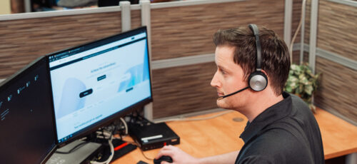 IT support expert sits at a desk with a headset on